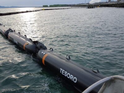 Floating barrier on water, factory background.