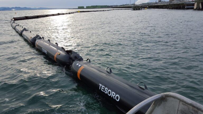 Floating barrier on water, factory background.