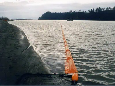 Orange floating barrier on calm water shoreline