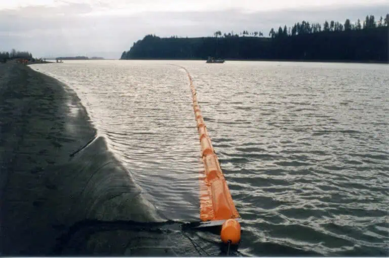 Orange floating barrier on calm water shoreline