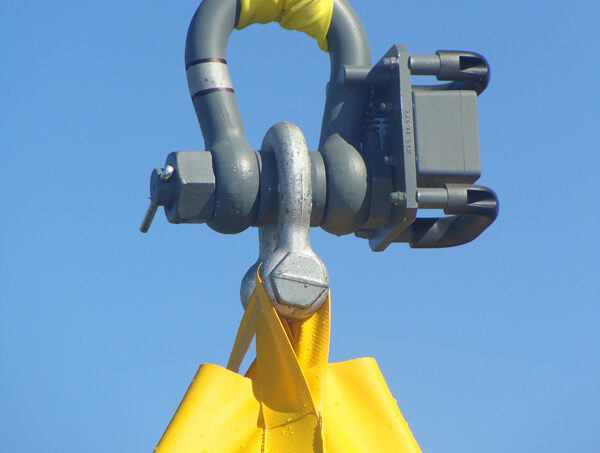 Crane lifting strap with industrial hook against blue sky.
