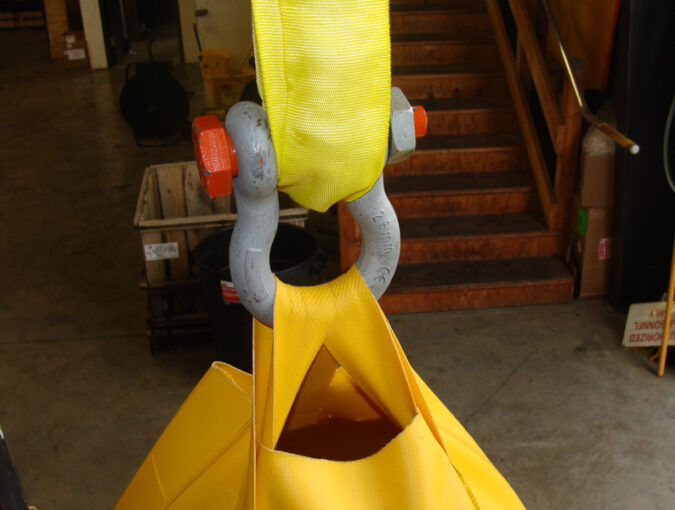 Industrial lifting hook with yellow straps.