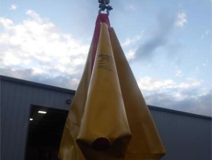 Industrial lifting bag suspended by crane outdoors.