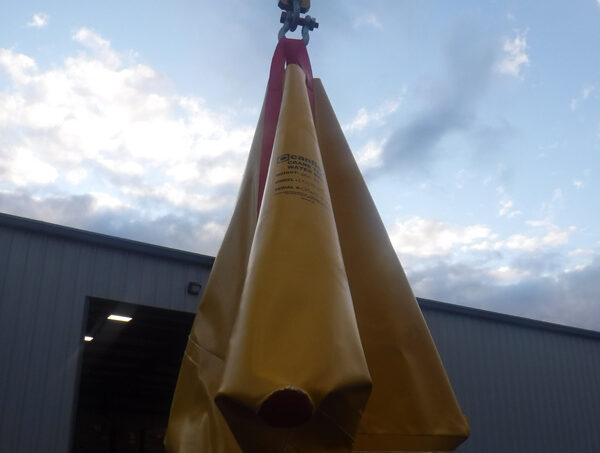 Industrial lifting bag suspended by crane outdoors.