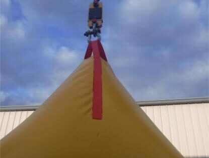 Crane lifting yellow object against cloudy sky.