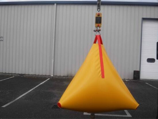 Yellow buoys suspended by crane against building.