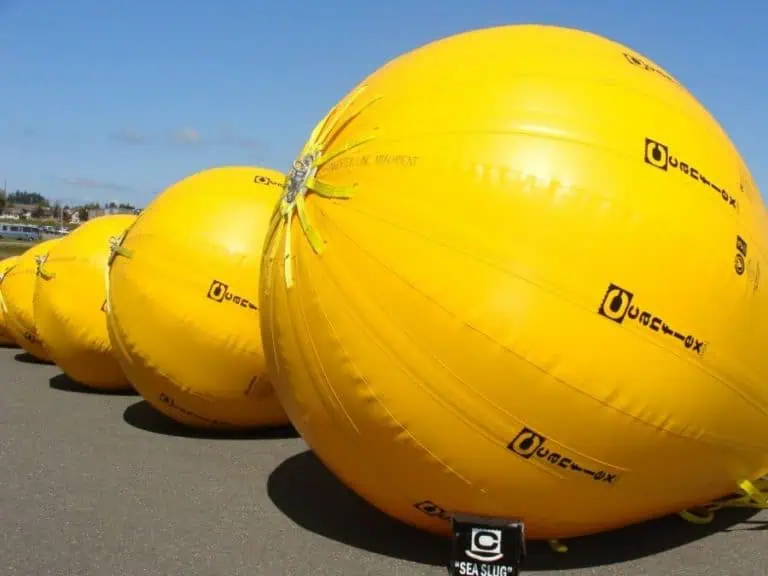 Large yellow floating marine buoys on land.