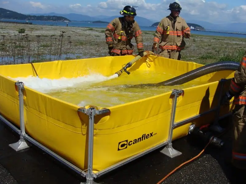 Firefighters using yellow portable water tank.