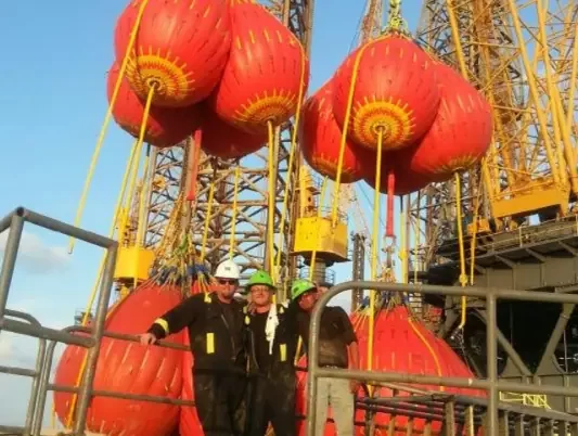 Workers with large orange crane load tests.