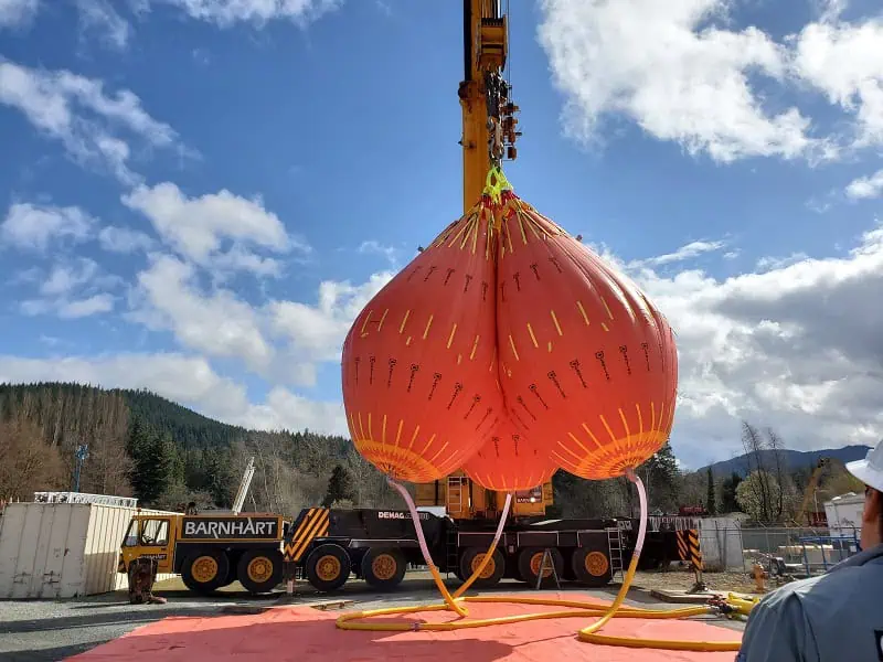 Large orange test weights suspended by crane.