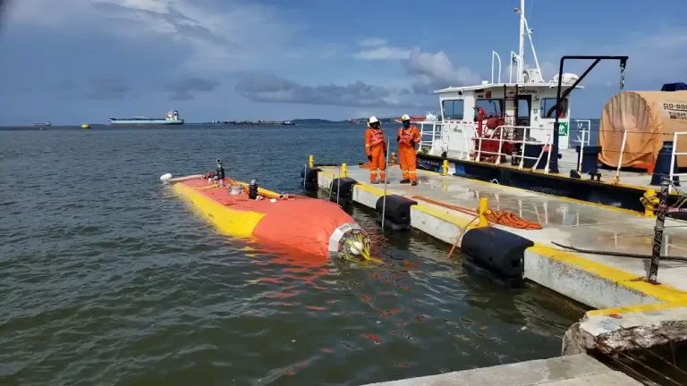 Workers inspect submarine at dock.