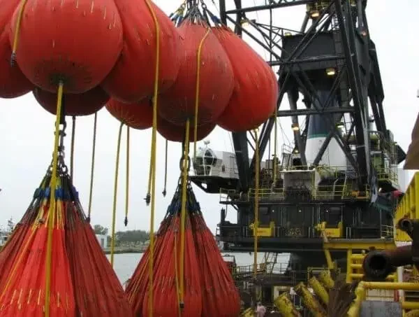 Crane lifting heavy load with large orange bags