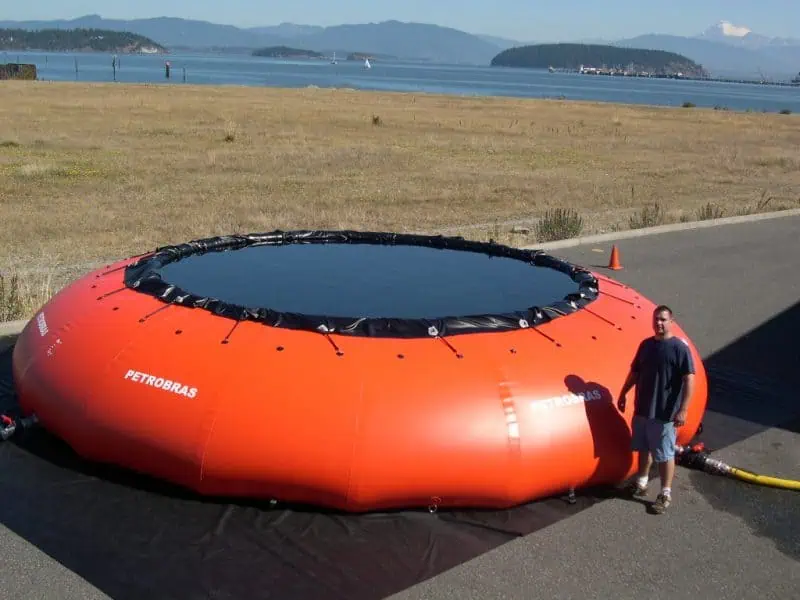 Large inflatable tank at harbor with person standing.