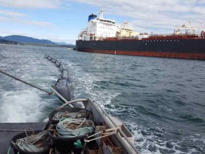 Oil spill containment operations near large tanker ships.