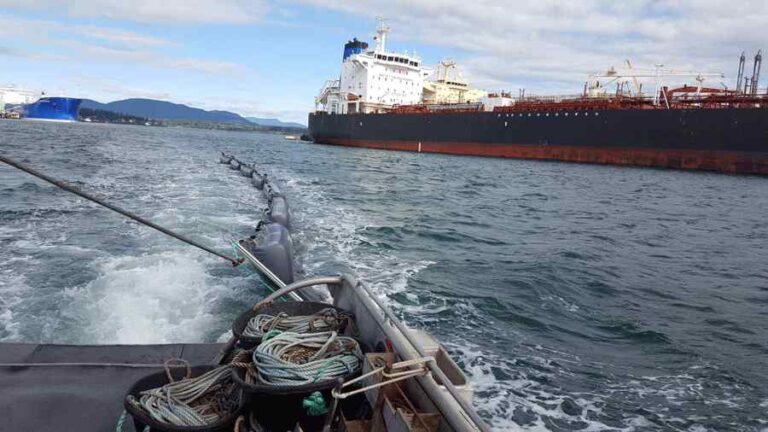 Oil spill containment operations near large tanker ships.