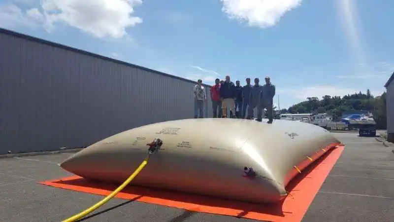 People standing on large industrial water storage bladder.