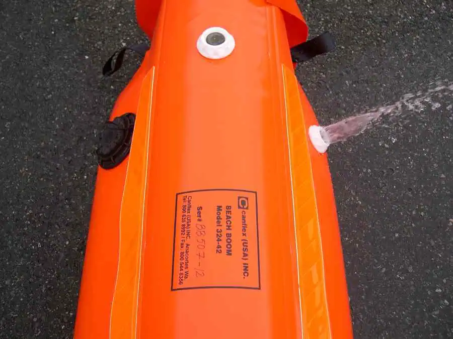 Orange inflatable boom leaking water on pavement