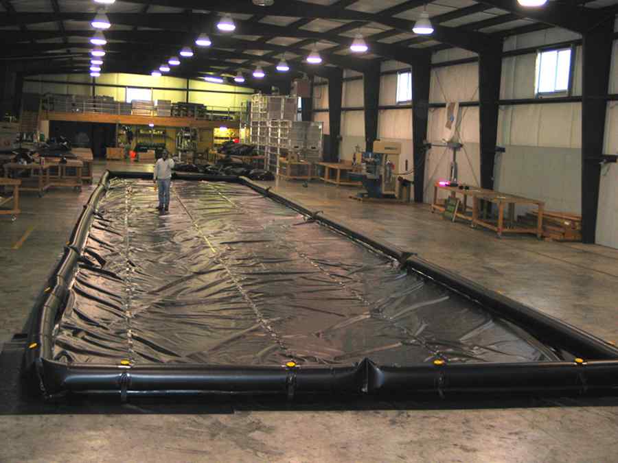 Person inspecting large black containment pool in warehouse