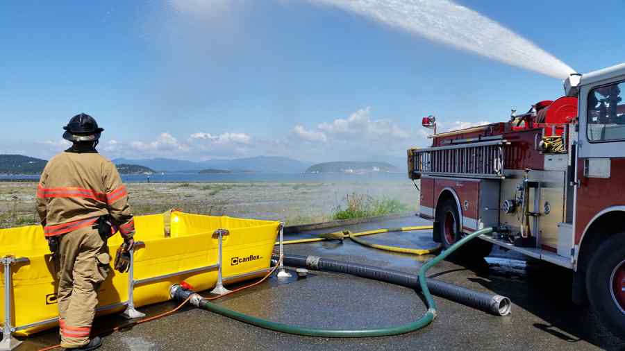 Firefighter operating water tank and fire truck outdoors