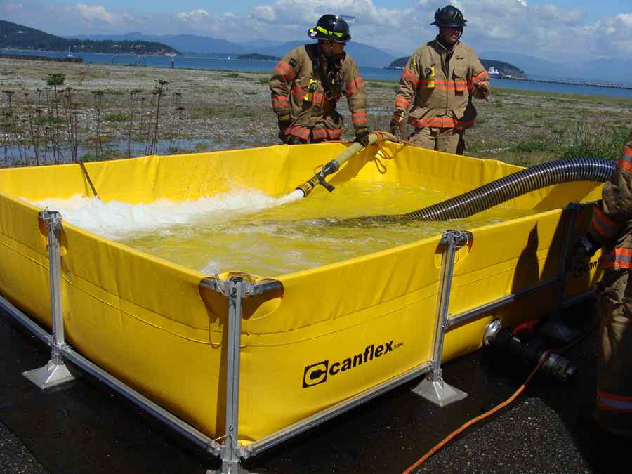 Firefighters filling portable water tank outdoors