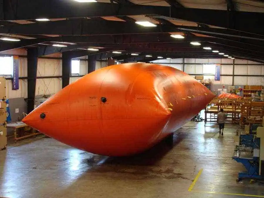 Large orange inflatable structure inside warehouse