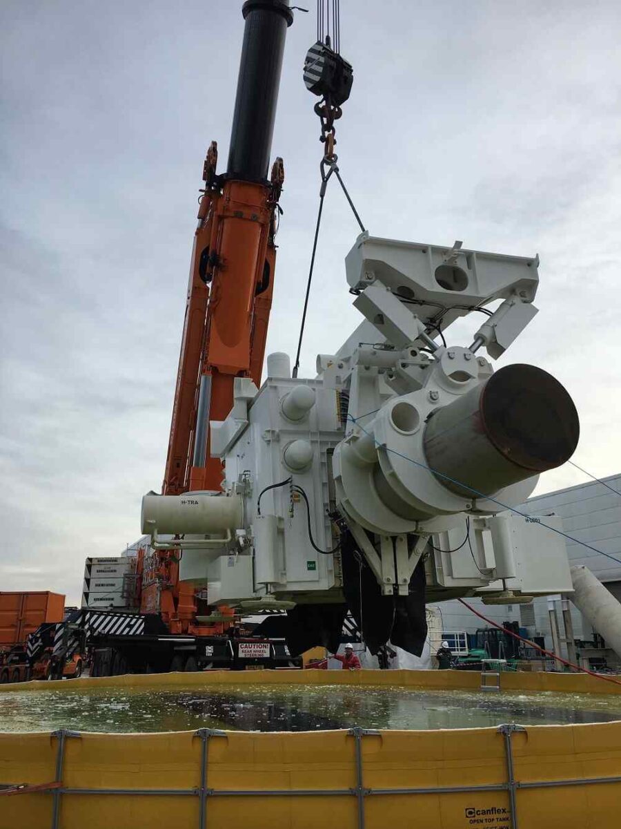 Crane lifting large industrial equipment at construction site