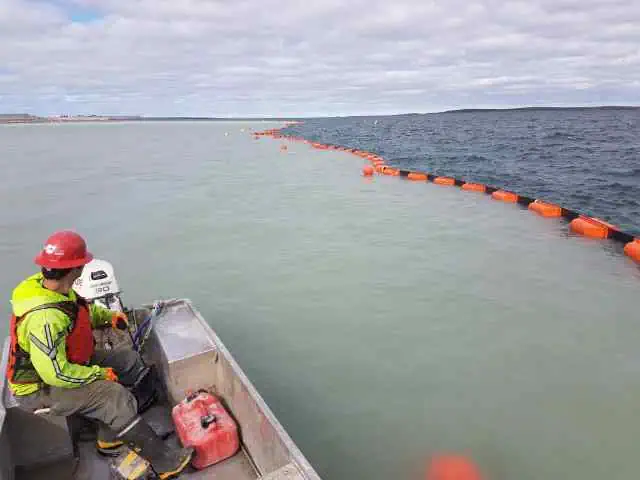Worker observing floating barrier dividing water colors
