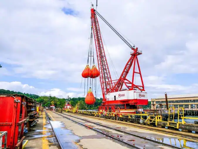 Large red crane lifting heavy load outdoors