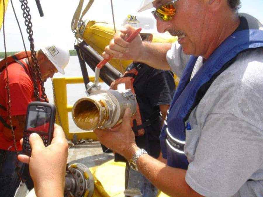 Workers applying grease to metal pipe joint