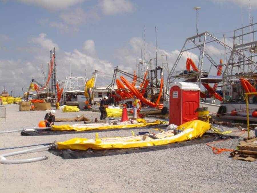 Workers preparing boats with oil containment booms