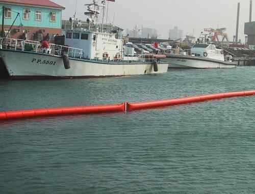 Boats docked near floating oil containment boom