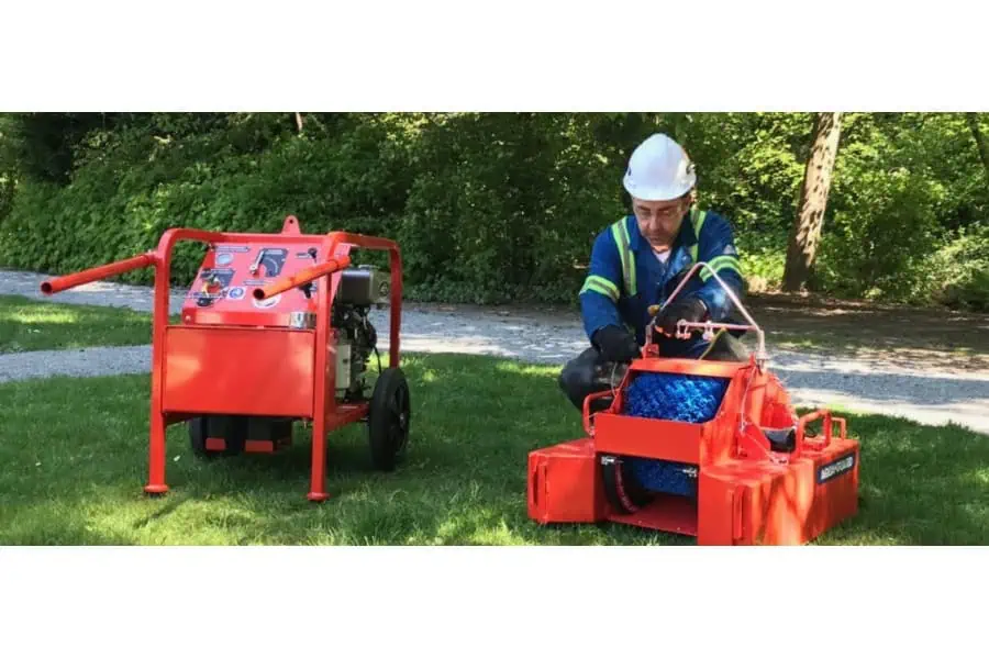 Worker operating orange industrial cleaning equipment outdoors