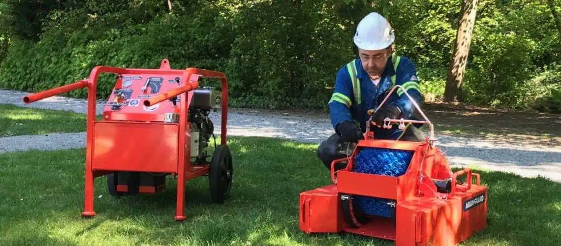 Worker operating orange industrial cleaning equipment outdoors