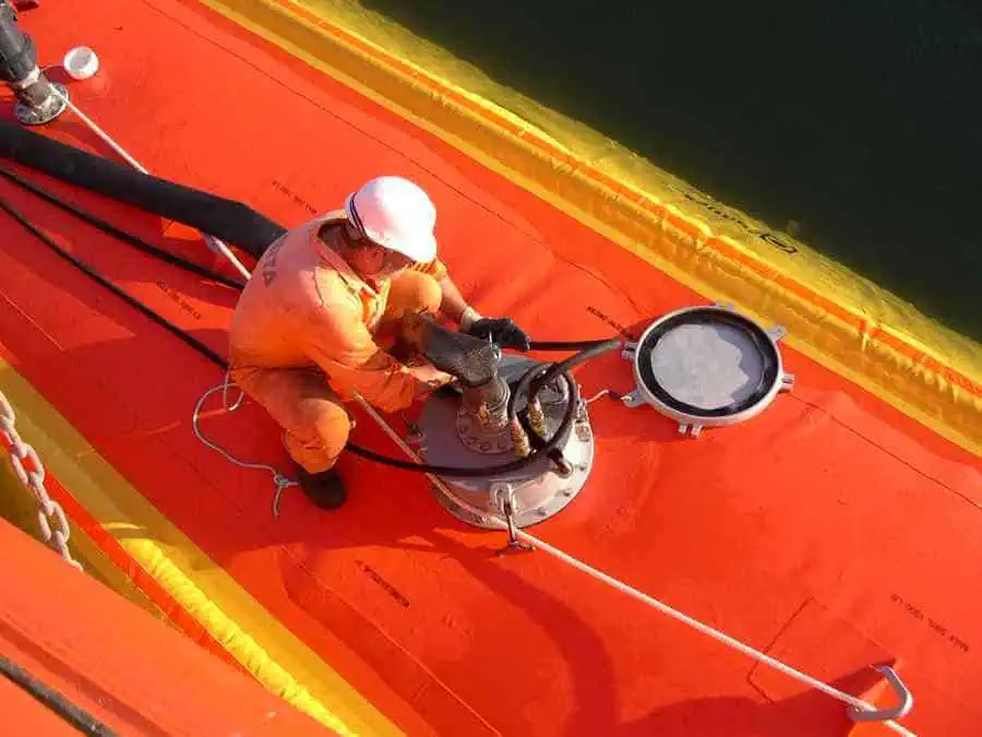 Worker connecting hose on industrial tank