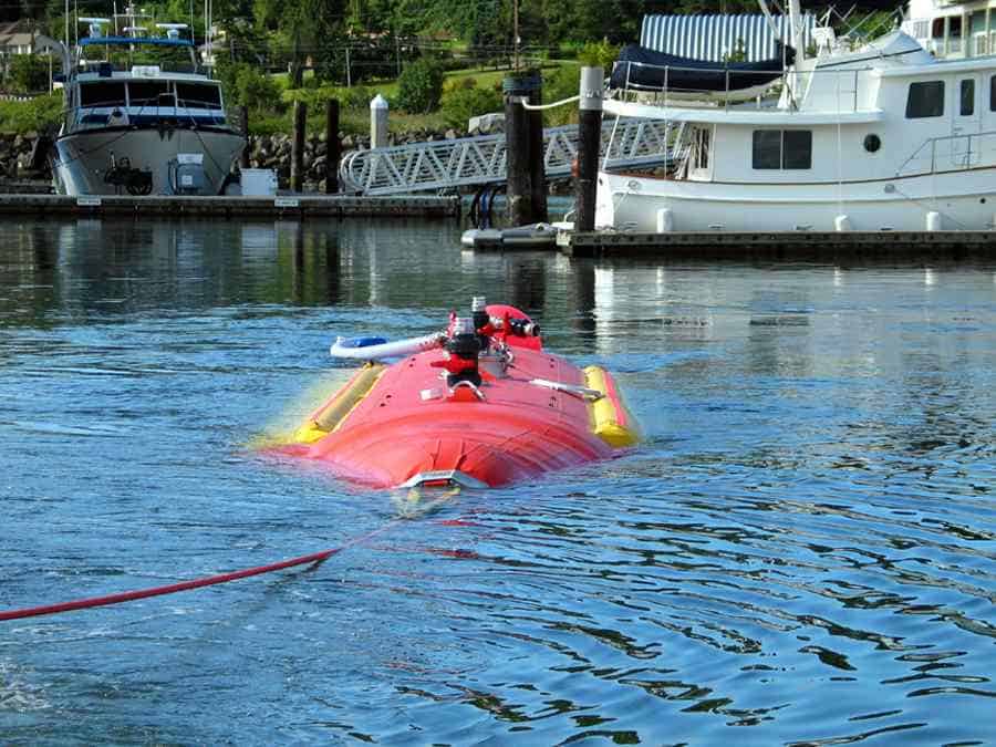 Red submarine floating near docked boats