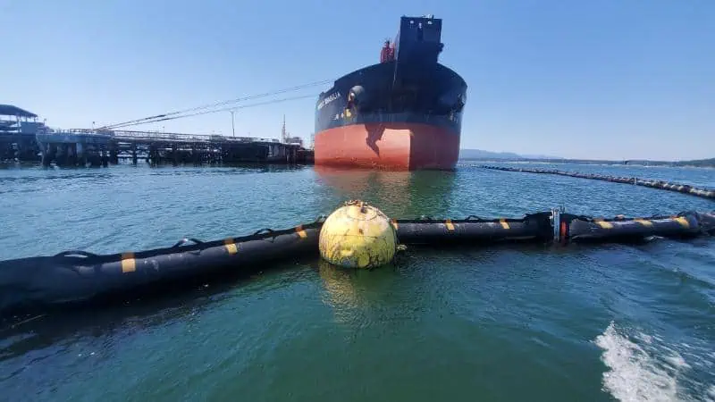 Large cargo ship docked near floating barriers