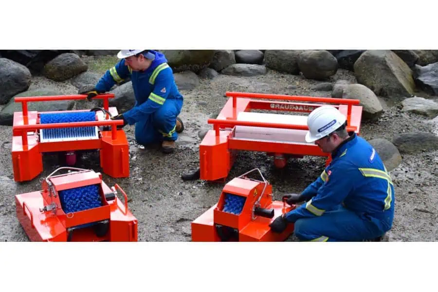 Workers inspecting orange industrial cleaning equipment outdoors