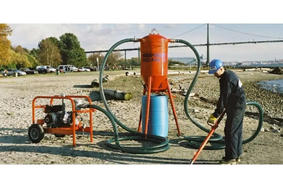 Worker cleaning beach using industrial vacuum equipment