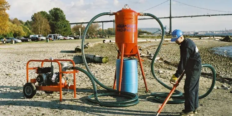 Worker cleaning beach using industrial vacuum equipment