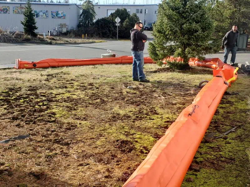 Workers inspecting orange equipment on grassy area