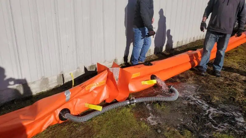 Workers testing orange flood barrier by building wall