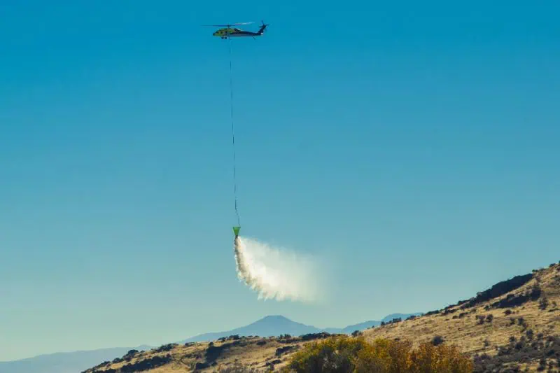 Helicopter dropping water over a dry hillside