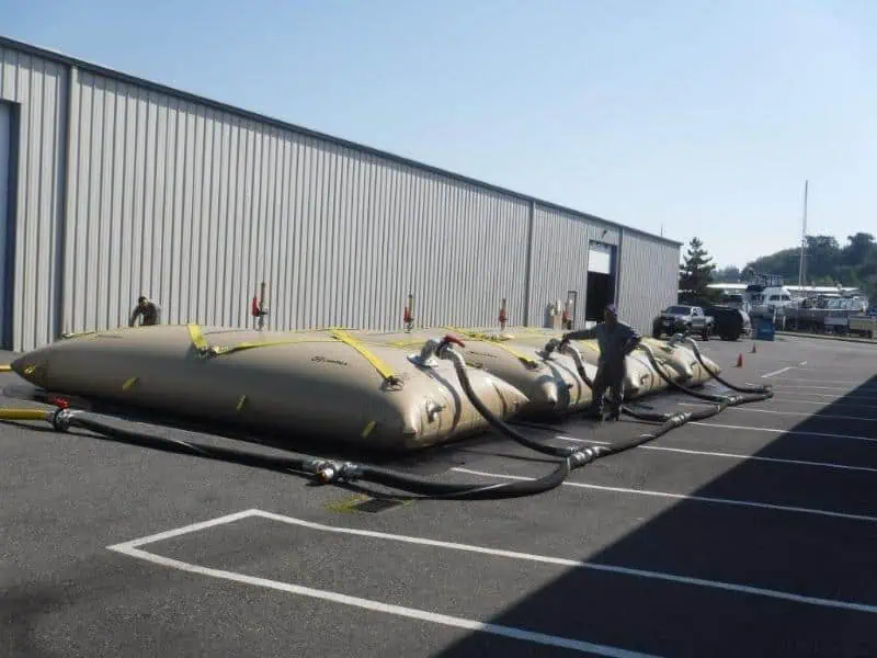 Workers connecting large water storage bladders outdoors