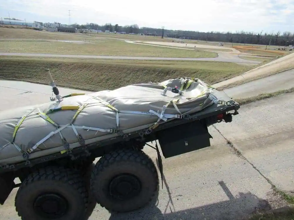 Military vehicle transporting covered equipment on test track