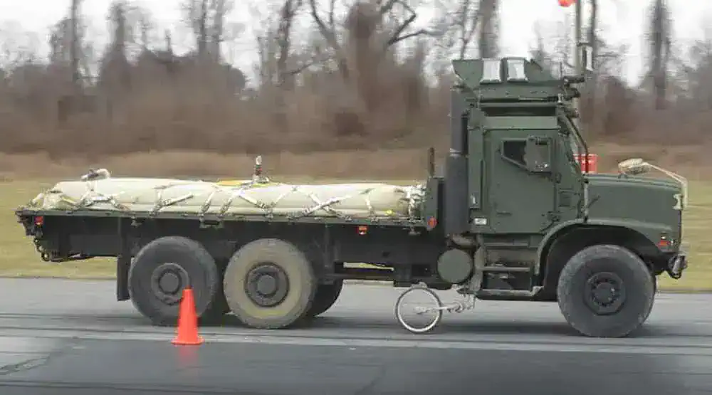 Military truck carrying large equipment on road