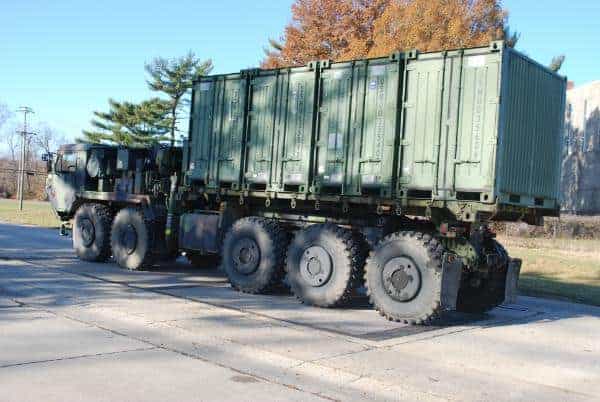 Military cargo truck carrying large green containers