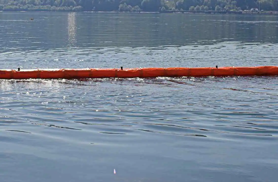 Orange oil containment boom floating on water