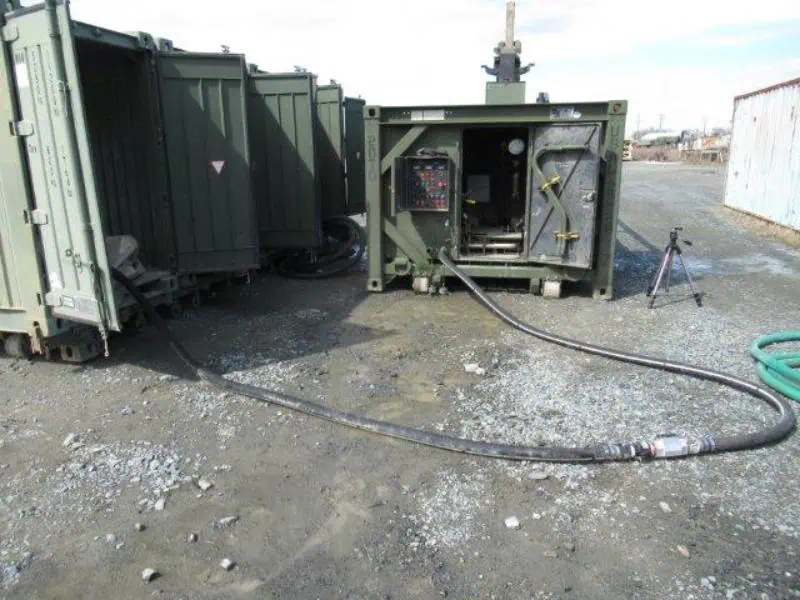 Industrial containers connected by heavy hoses outdoors