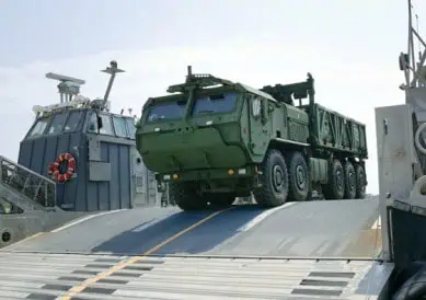 Military truck loading onto naval ship ramp