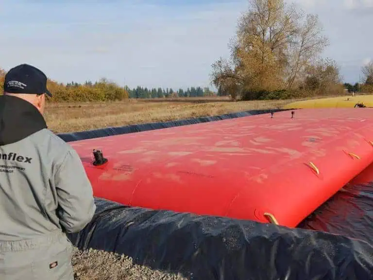 Worker inspecting large red water storage bladder
